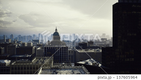 Dusk urban skyline with shadowed tower at left and capitol dome centered, soft fading light and atmospheric haze, layered rooftops and distant towers creating Dusk urban skyline with shadowed tower at left and capitol dome centered, soft fading light and atmospheric haze, layered rooftops and distant towers creating 137605964