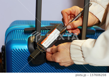 Labeling a Blue Suitcase with a Bright Orange Luggage Tag Labeling a Blue Suitcase with a Bright Orange Luggage Tag 137606208