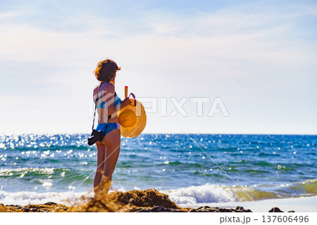 Woman in bikini with camera walk on beach 137606496