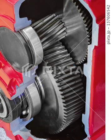 Close view of mechanical gears inside a red engine casing during assembly in a workshop setting 137606542