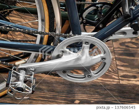 Close view of bicycle crankset and pedal showing metal and chain details in an indoor setting during daytime Close view of bicycle crankset and pedal showing metal and chain details in an indoor setting during daytime 137606545