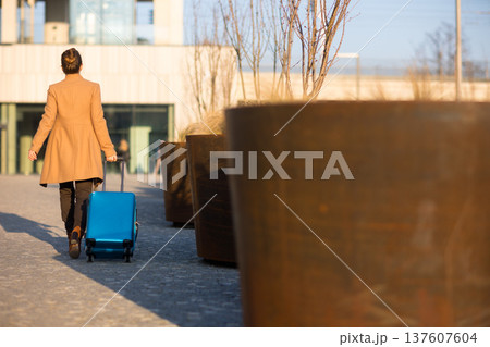 Woman Walking with Luggage Outside Modern Railway Station Woman Walking with Luggage Outside Modern Railway Station 137607604