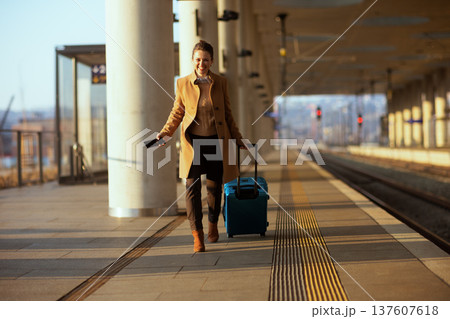 Smiling Woman Traveler with Suitcase at Train Station 137607618