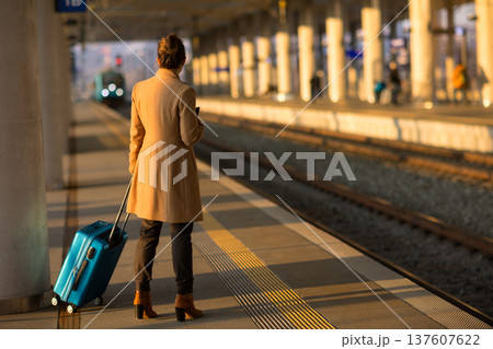 Woman with Blue Suitcase Waiting on Train Station Platform Woman with Blue Suitcase Waiting on Train Station Platform 137607622