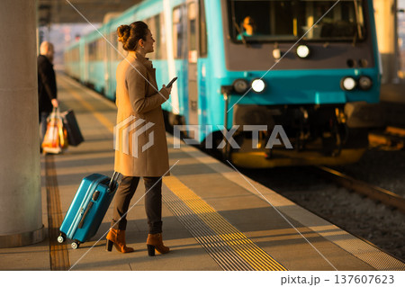 Modern Female Traveler Using Phone Near Departing Train Modern Female Traveler Using Phone Near Departing Train 137607623