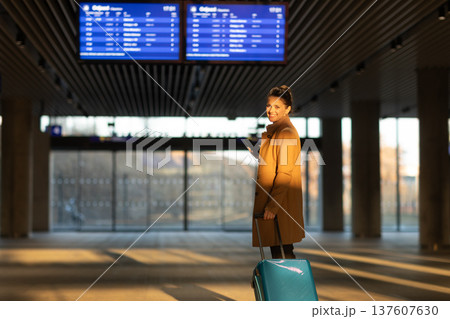 Smiling Woman Checking Train Times at Departure Board 137607630