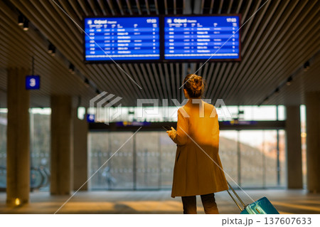 Woman with Suitcase and Phone in Modern Railway Terminal 137607633