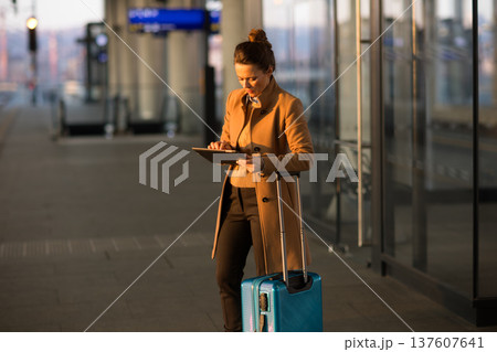 Woman Checking Train Schedule on Tablet at Station Woman Checking Train Schedule on Tablet at Station 137607641
