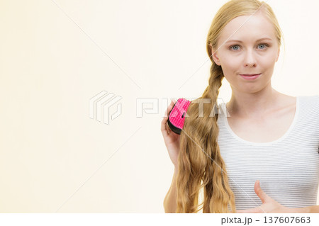 Blonde girl brushing her long hair 137607663