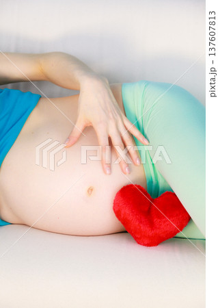 Pregnant woman lying on couch touching her belly 137607813