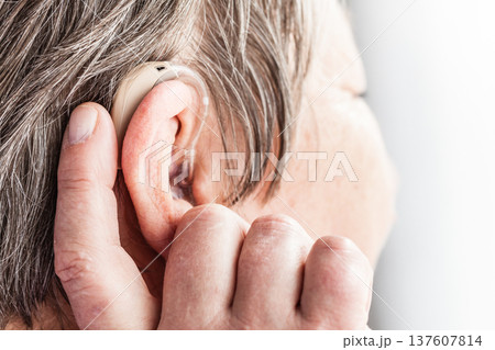 Closeup senior woman using hearing aid Closeup senior woman using hearing aid 137607814