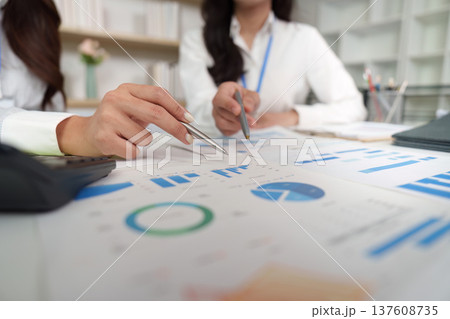 Business Collaboration. Two professionals analyzing financial data and charts during a meeting. 137608735