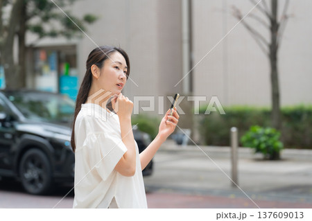 女性　カジュアル　初夏　スマホ　悩む 137609013