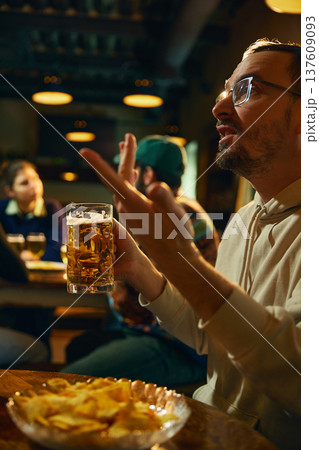 Beer glass in hand during conversation in pub bar with friends enjoying social drinking and relaxed nightlife 137609093