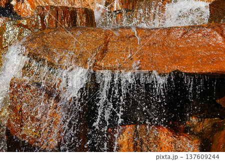 Waterfall close-up background, texture. Water flowing over rocky stones, splashes drops. Waterfall close-up background, texture. Water flowing over rocky stones, splashes drops. 137609244