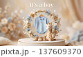 Baby Boy Announcement with Blue Knit Romper Plush Giraffe Toy in Dried Flower Wreath on Podium 137609370