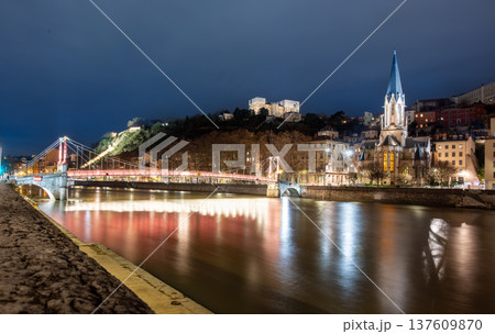 Lyon, france. December 29, 2023. Lyon cityscape at night showcasing the illuminated passerelle saint georges and saint georges church reflecting in the calm saone river 137609870