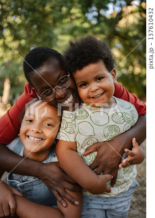 Mother Embracing her Two Children in a Park 137610432