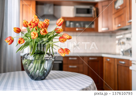Tulips bouquet in white vase on kitchen table interior Tulips bouquet in white vase on kitchen table interior 137610793