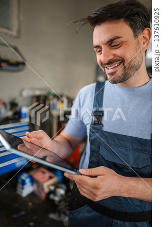Smiling mechanic using a digital tablet in a workshop Smiling mechanic using a digital tablet in a workshop 137610925