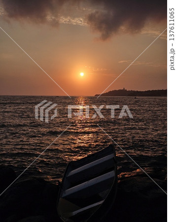 A fishing boat wreck rests on rocks at Kusadasi cliffs during golden hour in Turkey, Close-up shot of a beached shipwreck along the coast of Kusadasi, Augen, Turkey. 137611065