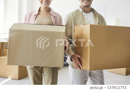 Happy proud couple holding cardboard boxes together when moving into new home 137611755