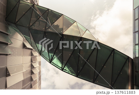 a mesmerizing, twisted sky bridge crafted from reflective glass and geometric precision, bridging modern structures at the Tottenham Hotspur stadium complex. Linking Lilywhite House's administrative a mesmerizing, twisted sky bridge crafted from reflective glass and geometric precision, bridging modern structures at the Tottenham Hotspur stadium complex. Linking Lilywhite House's administrative 137611883