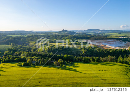 The countryside of Bohemian Paradise in Czechia during summer. Trosky Castle stands on a hill overlooking the green fields and forests. The countryside of Bohemian Paradise in Czechia during summer. Trosky Castle stands on a hill overlooking the green fields and forests. 137612356