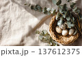 Natural Easter nest with speckled quail eggs and eucalyptus branches on linen fabric, rustic spring decoration scene inspired by organic countryside lifestyle 137612375