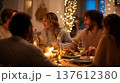 Friends sharing cozy dinner at candlelit table, warm evening celebration with food, wine and laughter creating festive atmosphere and community lifestyle moment 137612380