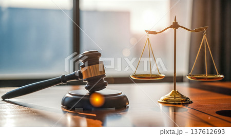 Wooden judge gavel and golden scales of justice standing on desk in modern lawyer office with bright sunlight window background representing legal system 137612693