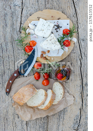 Sliced ciabatta bread, cheese, tomatoes and spices lying on wooden table Sliced ciabatta bread, cheese, tomatoes and spices lying on wooden table 137613552