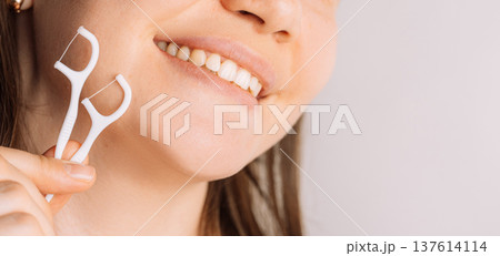 Smiling woman holding floss pick near teeth, oral hygiene and dental care concept Smiling woman holding floss pick near teeth, oral hygiene and dental care concept 137614114