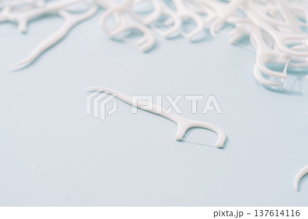 Single dental floss pick on light blue background with scattered flossers, minimal oral care concept Single dental floss pick on light blue background with scattered flossers, minimal oral care concept 137614116