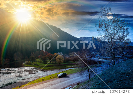 mountain landscape during fall season. day meet night. sun and moon over rural scenery with river at twilight. composite image of a countryside road through valley near village for travel background 137614278