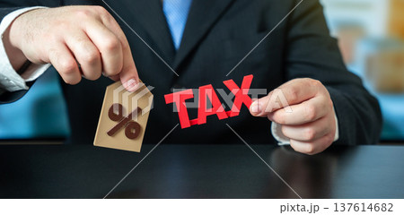 A businessman holding the word Tax and a percentage sign. Business and finance concept. taxation, Taxes rates, fiscal policy, financial obligations, and economic regulation. Taxation 137614682