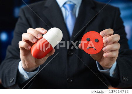A medical capsule and displeased smiley face in hand 137614752