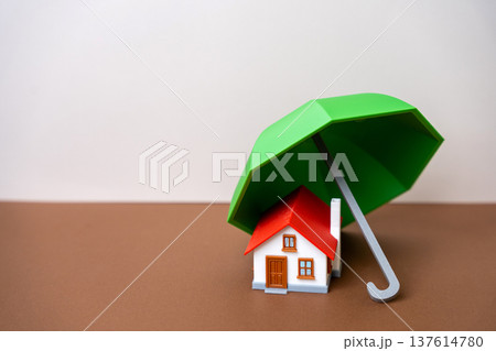 Concept of security and property insurance. Home safety, mortgage protection, real estate investment, family assets. Umbrella and a small house. copy space 137614780