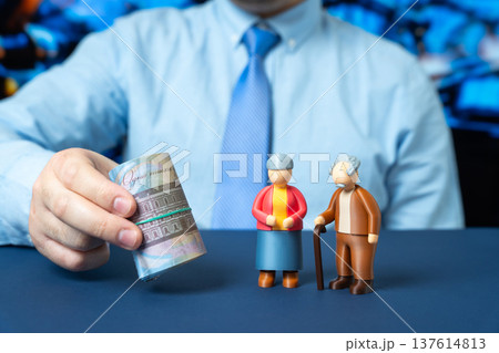 Businessman holding Ukrainian hryvnia near figurines of an elderly couple. Pension funding, retirement savings, and financial support for the aging population. Ukraine people support 137614813