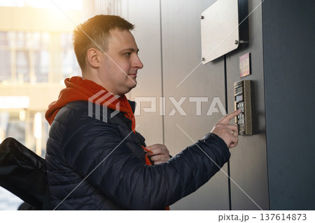 Beautiful 35 year old caucasian man presses the apartment number or the code on the intercom. 137614873