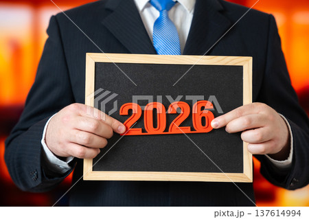 A businessman holds the year 2026 in his hands. New Year in business and commerce. 137614994