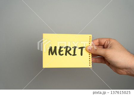 Concept of achievement and recognition. Merit symbolizes success, perseverance, and inner worth a visual metaphor for accomplishment and value. Note in hand with the word Merit Concept of achievement and recognition. Merit symbolizes success, perseverance, and inner worth a visual metaphor for accomplishment and value. Note in hand with the word Merit 137615025