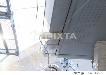 住宅の外壁塗装工事で軒天をローラーで塗る職人の手元 137615499