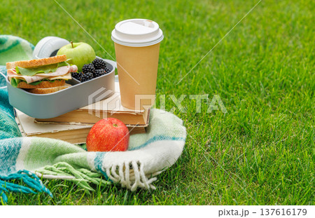 Picnic on a lawn with books, sandwiches, fruits, and coffee Picnic on a lawn with books, sandwiches, fruits, and coffee 137616179