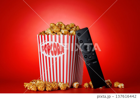 Popcorn and TV remote on red background Popcorn and TV remote on red background 137616442
