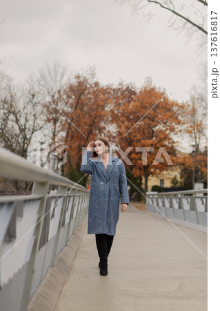 Beautiful young girl stands on an iron bridge near 137616817