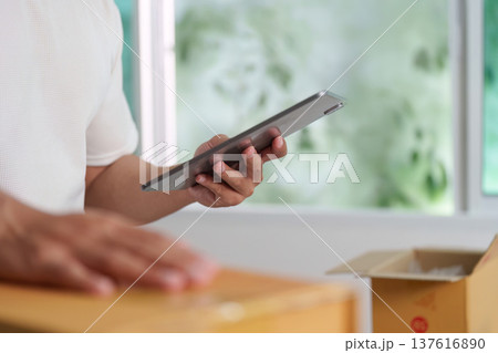 Digital Inventory Check. A man using a tablet to manage stock in a modern office. 137616890