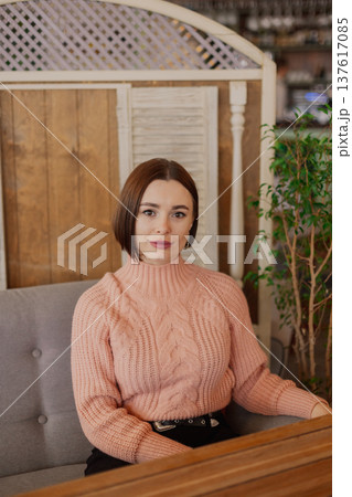 Beautiful young girl sitting at a table in a 137617085