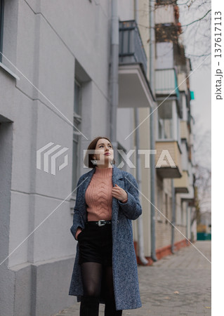 Beautiful young girl walking along an old street 137617113