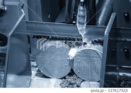Industrial band saw machine operation cutting a metal rod using high-efficiency liquid coolant for thermal management. Industrial band saw machine operation cutting a metal rod using high-efficiency liquid coolant for thermal management. 137617428